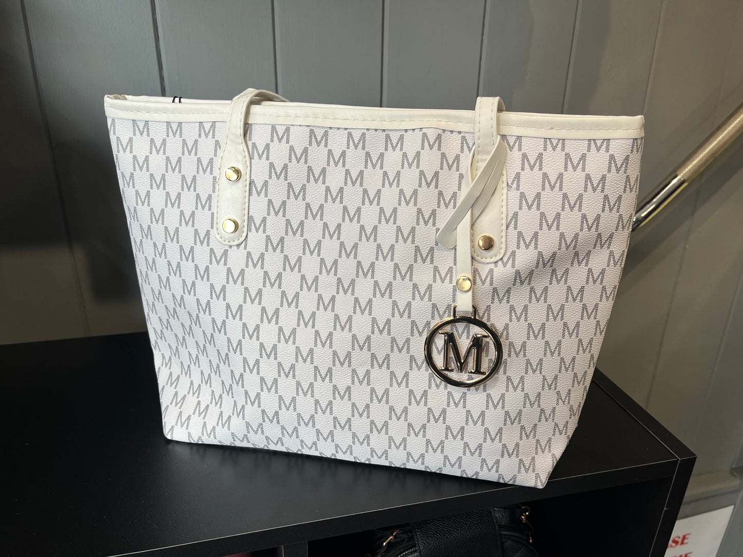 White tote bag with repeating monogram pattern and circular M logo
